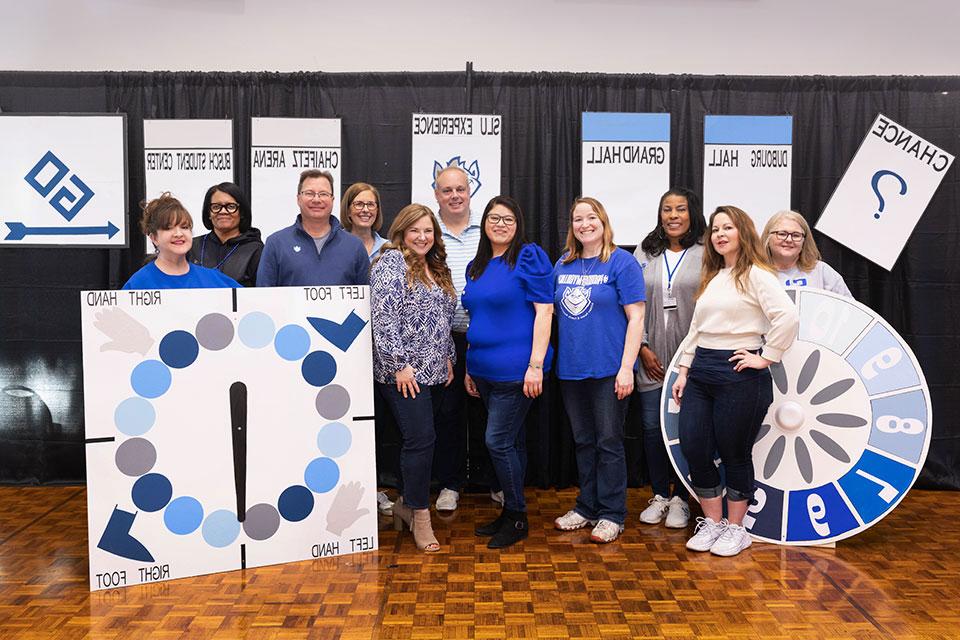 Eleven BPFA board members standing in front of board-game themed trivia night decorations.